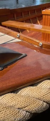 Een detailfoto van een houten boot met een navigatielicht, een touwstootrand en een teakhouten dek. — De Jongvlet 6.20