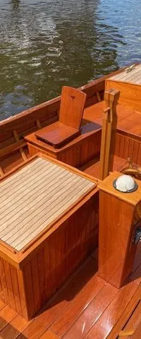 Een houten boot met een Nederlandse vlag aan de achtersteven, liggend in het water. — De Jongvlet 6.20