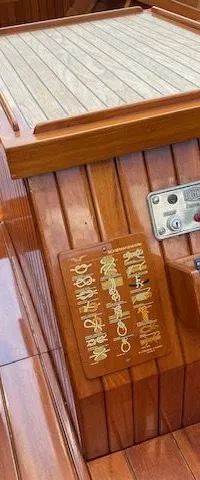Een houten stuurwiel, een bedieningspaneel en diverse houten panelen met symbolen zijn zichtbaar in een houten boot.