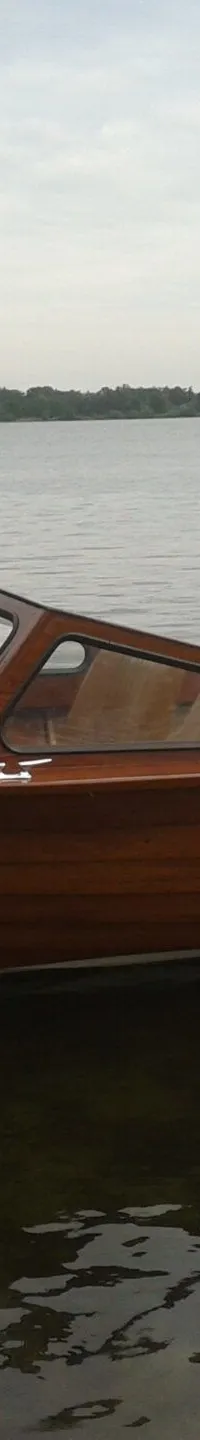 Een houten motorboot met een Yamaha buitenboordmotor ligt in het water, met een kenteken 96-95-YP op de zijkant.