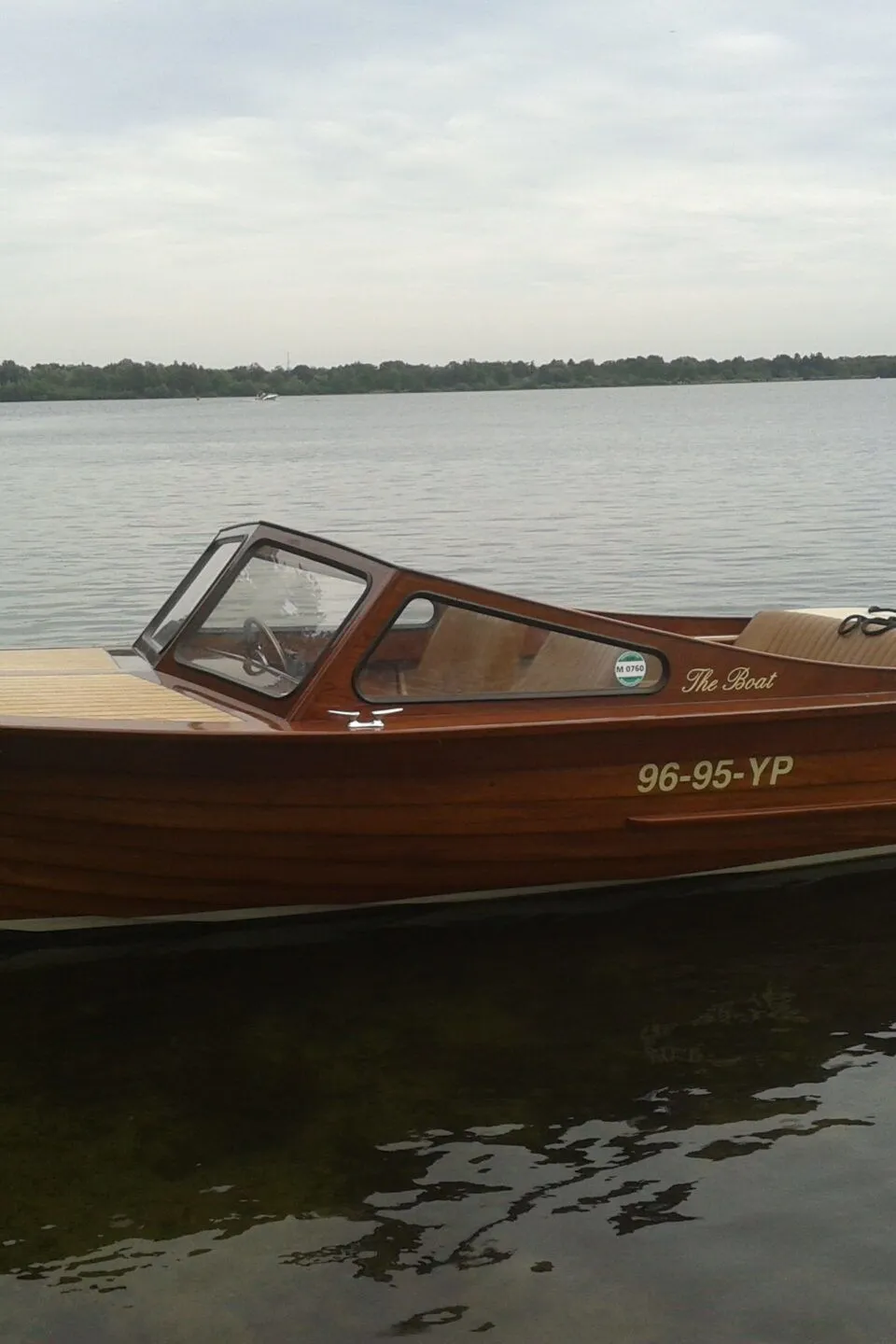 Een houten motorboot met een Yamaha buitenboordmotor ligt in het water, met een kenteken 96-95-YP op de zijkant.