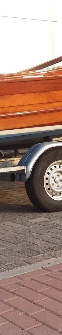 Een houten boot met een Yamaha buitenboordmotor staat op een trailer geparkeerd op een stenen oprit. — Flying Finn 19.60