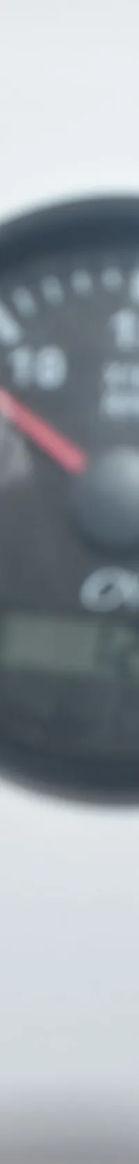 Een close-up van een wit dashboard met vijf ronde, zwarte meters, waarvan de middelste het grootst is.
