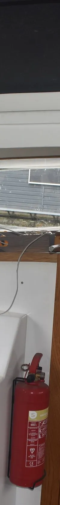 De foto toont het interieur van een boot met een stuurwiel, dashboard, brandblusser en houten deuren. — 820C Steilsteven