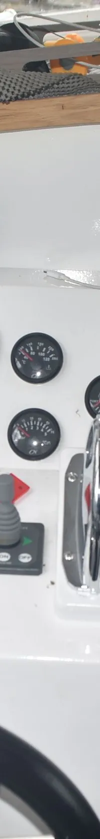 Een wit dashboard met diverse meters, schakelaars, een gashendel, een stuurwiel en een rode brandblusser.