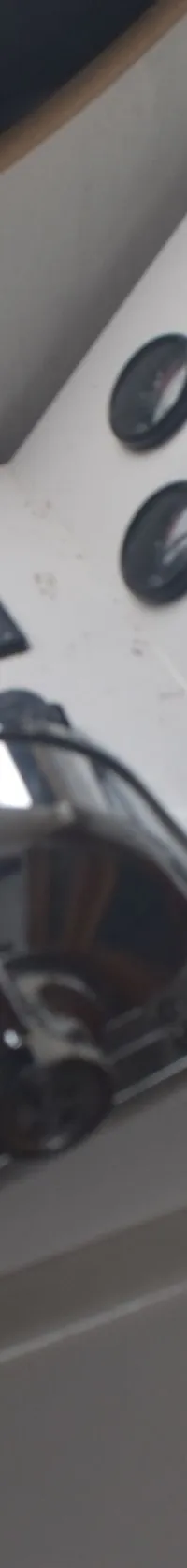 Een stuurstand met een zwart stuurwiel, een gashendel, diverse meters en een brandblusser.
