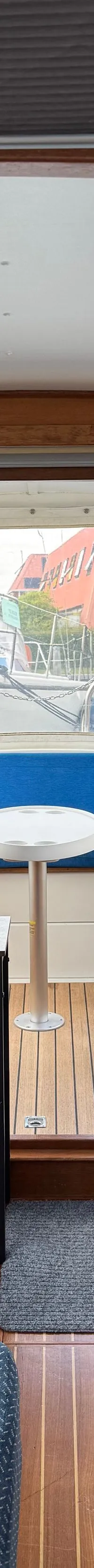 De foto toont het interieur van een boot met houten wanden en vloer, blauwe zitbanken en een stuurstoel.