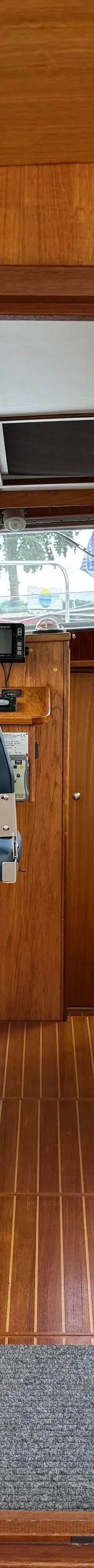 Een interieur van een boot met houten wanden en vloer, een stuurstand, een bank en een tafel. — Drammer 8.20 Classic