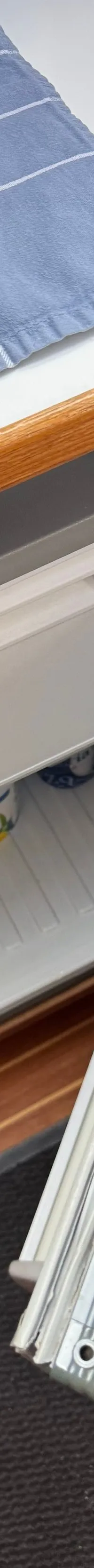 Een open koelkast in een boot met een blauw geruit doek, een gootsteen en een houten interieur. — Drammer 8.20 Classic