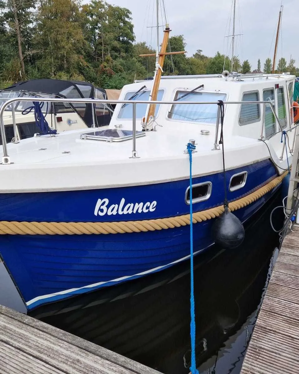 Een blauw-witte boot met de naam "Balance" ligt afgemeerd aan een houten steiger. — Drammer 8.20 Classic