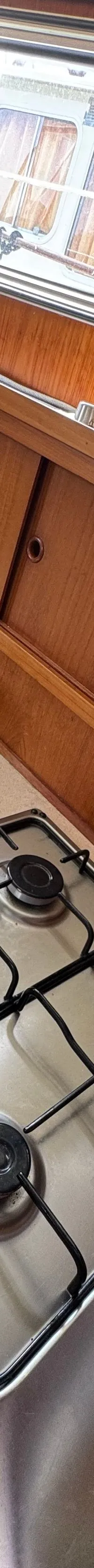 Een keukenblok met een ronde spoelbak, een vierpits gasfornuis en een houten snijplank.