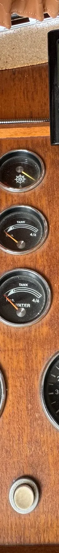 Een houten dashboard met diverse meters, schakelaars, een kompas en een digitaal display.