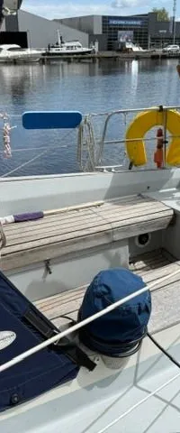 Een zeilboot ligt aangemeerd met een blauw afdekzeil over de giek en een houten roer. — Victoire 34 S-spant