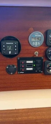 Een houten paneel met diverse meters, schakelaars en een bedieningspaneel voor een verwarming.