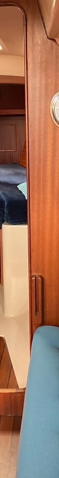 De foto toont het interieur van een boot met een houten afwerking, blauwe kussens en een navigatietafel met apparatuur.