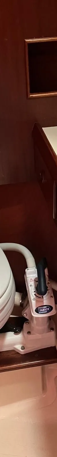 De foto toont het interieur van een boot met houten wanden, blauwe kussens en een tafel met een metalen paal.