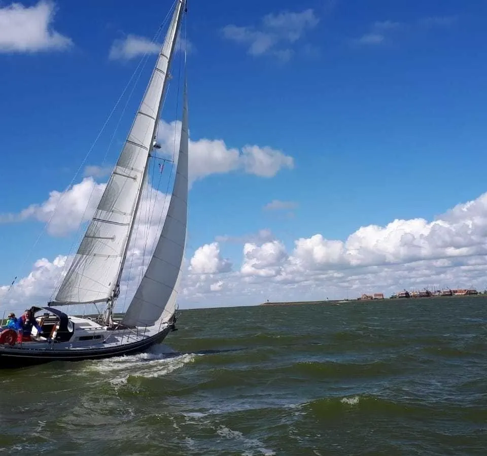 Een open opbergvak met diverse voorwerpen, een metalen pijp, een houten bankje en een houten dek.
