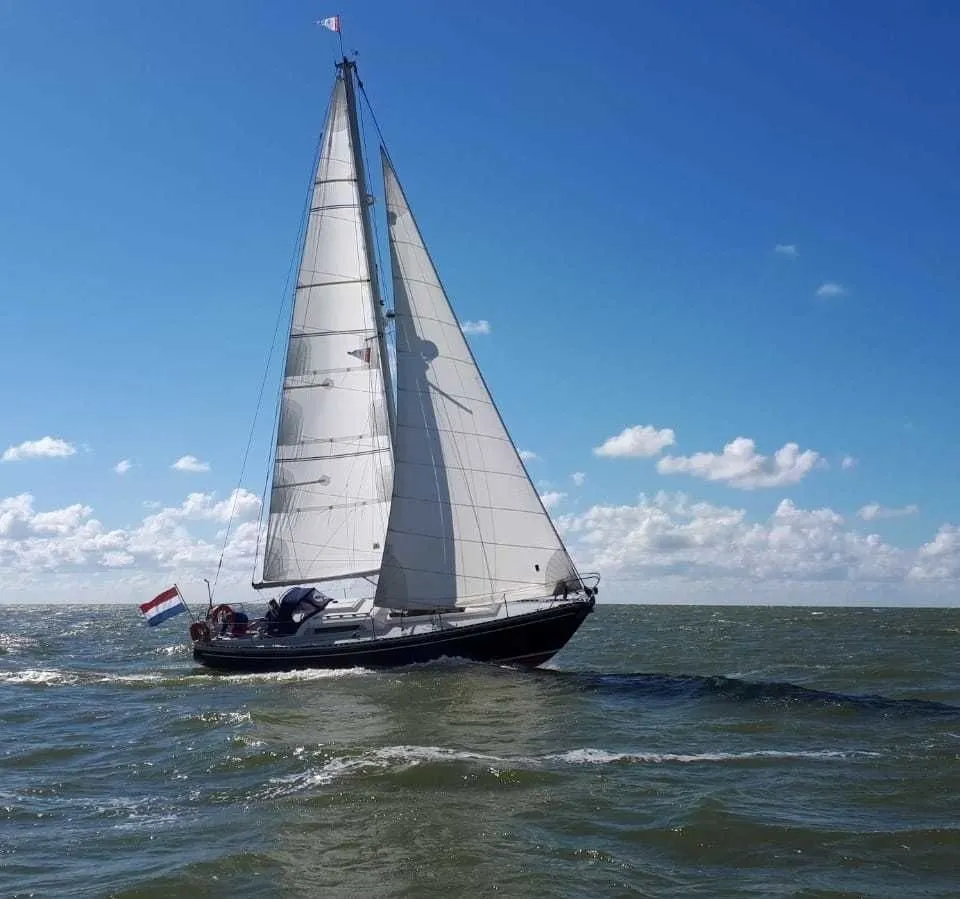 Een metalen plaatje met de tekst "Jachtwerf Frisia G.N.P. Vader Alkmaar Holland" is bevestigd op een witte ondergrond.