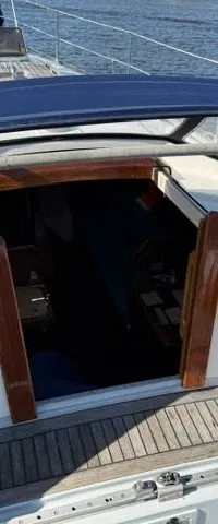 Een bovenaanzicht van de kuip van een zeilboot met een blauwe buiskap en een houten vloer. — Victoire 34 S-spant
