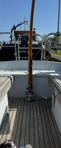 De foto toont de kuip van een zeilboot met houten banken en een houten vloer, met twee gele reddingsboeien aan de reling.