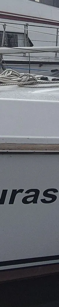 Een witte zeilboot met de naam "Turas" op de romp ligt aangemeerd in het water. — Contest 36 Ketch