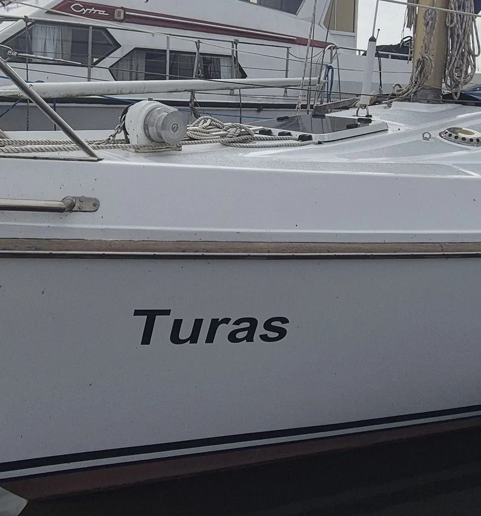 Een witte zeilboot met de naam "Turas" op de romp ligt aangemeerd in het water. — Contest 36 Ketch