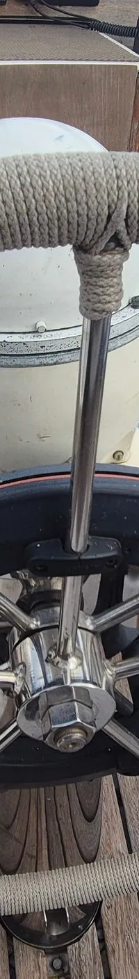 Een stuurwiel met touw omwonden, een kompas en een houten dek zijn zichtbaar op de boot. — Contest 36 Ketch