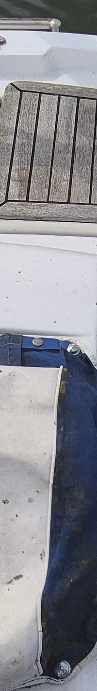 De foto toont het dek van een boot met houten luiken, een reddingsboei, touwen en een wit-blauw zeilhoes. — Contest 36 Ketch