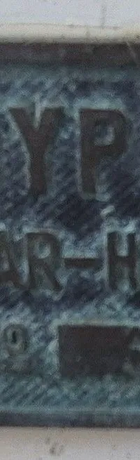 Een metalen plaatje met de tekst "CONYPLEX ALKMAAR-HOLLAND NO 5", vastgeschroefd met vier schroeven.