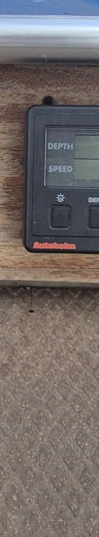 Een houten paneel met vier nautische instrumenten en een marifoon.