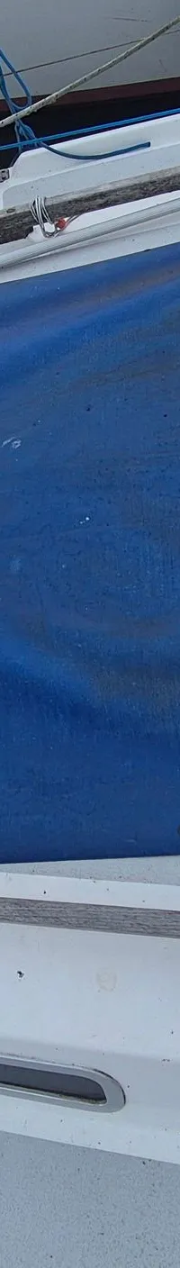 Een bovenaanzicht van een deel van een zeilboot met een blauw zeil, touwen, en een houten dek. — Contest 36 Ketch
