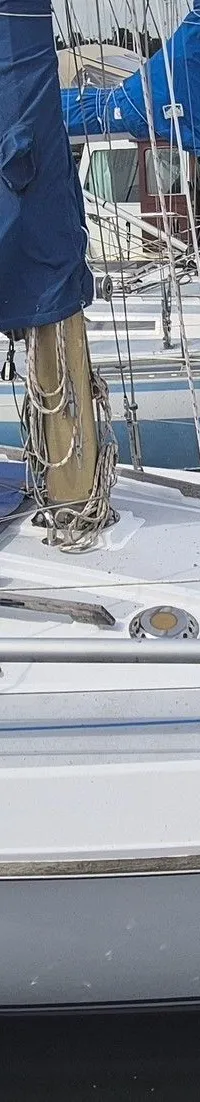 Een witte zeilboot met de naam "Turas" ligt afgemeerd in een haven, met een blauw zeilhoes en stootwillen. — Contest 36 Ketch