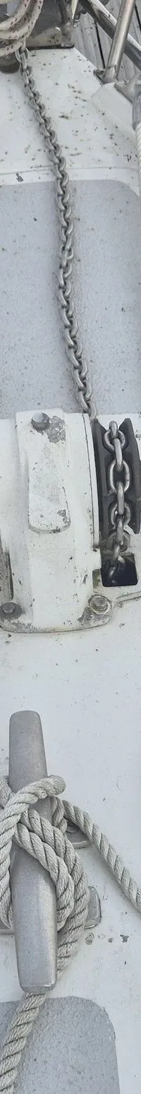 Een bovenaanzicht van de boeg van een witte zeilboot met grijze antislip, liggend aan een houten steiger. — Contest 36 Ketch