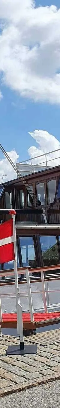 Een witte restaurantboot met bruine opbouw en ramen, genaamd "Restaurant Prinses Juliana", ligt aangemeerd.