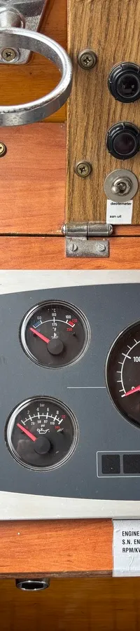 Een houten dashboard met diverse meters, schakelaars en bedieningselementen, waaronder een toerenteller en spanningsmeters.