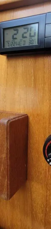 Een houten paneel met een digitaal display, een houten opbergvak en een ronde Webasto draaiknop.