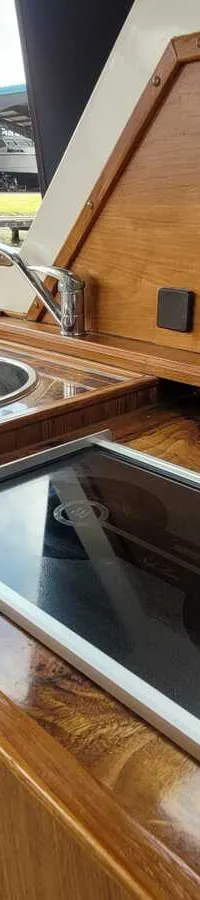 Een houten aanrechtblad met een ronde spoelbak en een glazen kookplaat is zichtbaar.