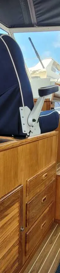 Een interieur van een boot met een blauwe stoel met "ASPER BOAT" erop, een wasbak en houten kasten. — Agder 840 OK