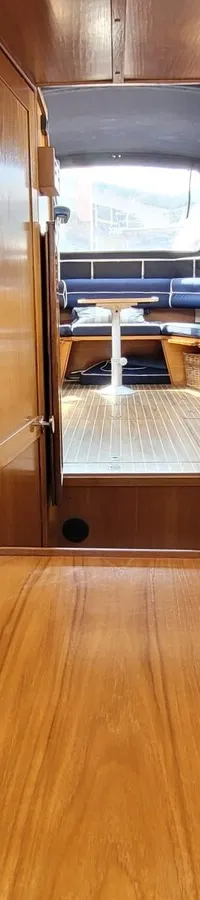 Een interieur van een boot met houten wanden, een houten tafel en blauwe kussens met witte stippen. — Agder 840 OK