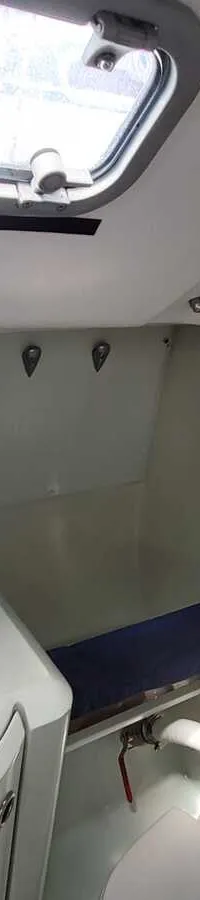 De foto toont een kleine badkamer of natte cel met een wastafel, spiegel, handdoekrek en een raam.