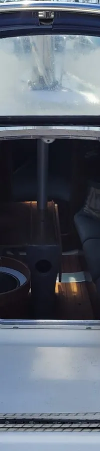 De foto toont het dek van een zeilboot met een open kajuitingang, omringd door touwen, lieren en Raymarine-apparatuur.