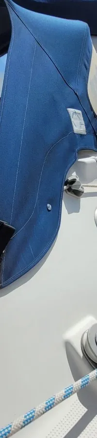 Een witte zeilboot met blauwe buiskap en zeilhuik, met een blauw logo op de kajuit. — Beneteau First 310