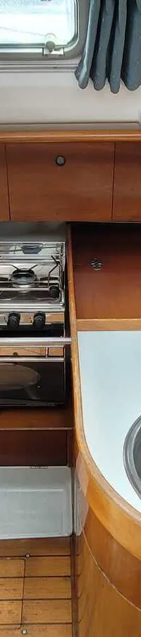 Een kombuis met een fornuis, oven, gootsteen en een waterkoker op het fornuis.