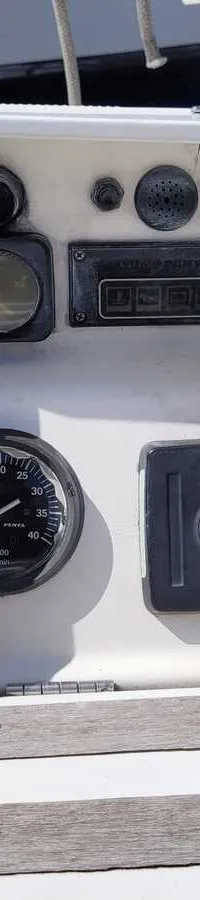 Een wit dashboard met een Raymarine-display, een toerenteller, een gashendel en diverse knoppen en meters.