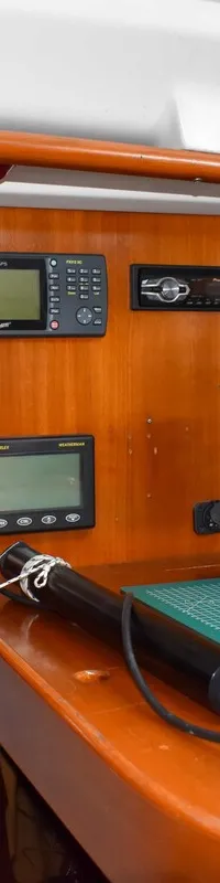 Een houten interieur van een boot met diverse navigatie-instrumenten, een radio en een schakelpaneel. — Beneteau First 310