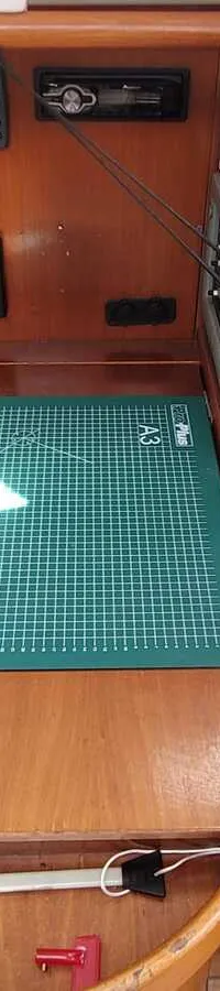Een houten navigatietafel met een groene snijmat, twee navigatie-instrumenten en een marifoon.