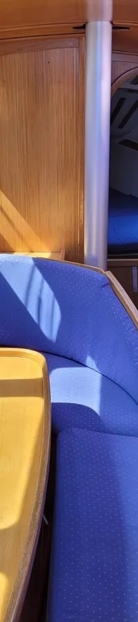 De foto toont het interieur van een boot met houten wanden, een blauwe U-vormige bank en een houten tafel. — Feeling 346