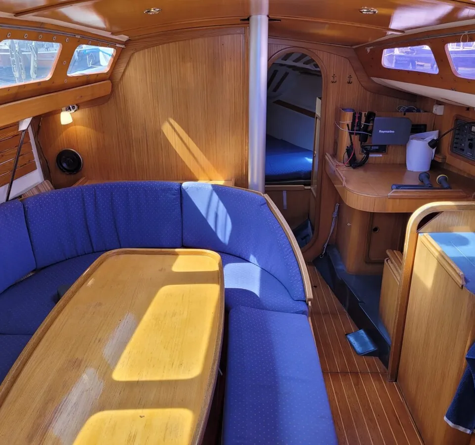 De foto toont het interieur van een boot met houten wanden, een blauwe U-vormige bank en een houten tafel. — Feeling 346