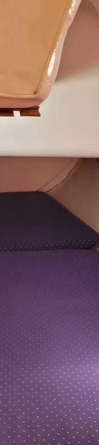 De foto toont een kajuit met twee paarse matrassen, een patrijspoort en houten details. — Feeling 346