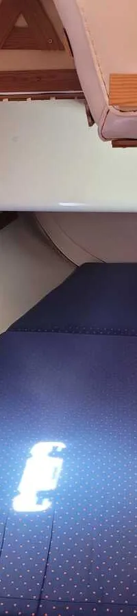 Een kajuit met een donkerblauw matras, houten kasten en een patrijspoort. — Feeling 346
